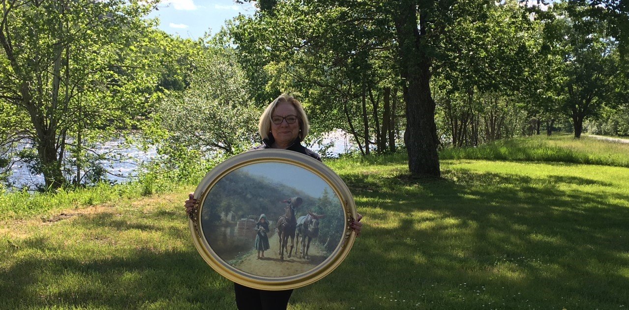 Historian Debra Conway holds a print of E.L. Henry’s 1891 painting, “On the Towpath,” which inspired her to propose a hiking trail on a former D&H Canal towpath, which is in the background to the right.